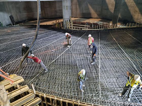 יציקת רמפה בחלל סגור, צוות פורק בטון מתפזר מעל רשת זיון רחבה ומיישר אותו